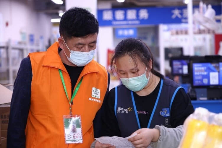 配圖說明：沃爾瑪員工在與綠洲志愿者進(jìn)行余量食物捐贈交接